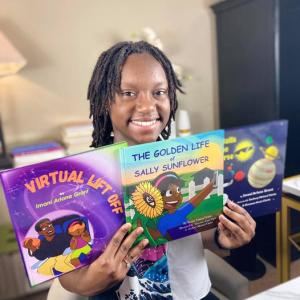 Child proudly holds up books she has written and published.