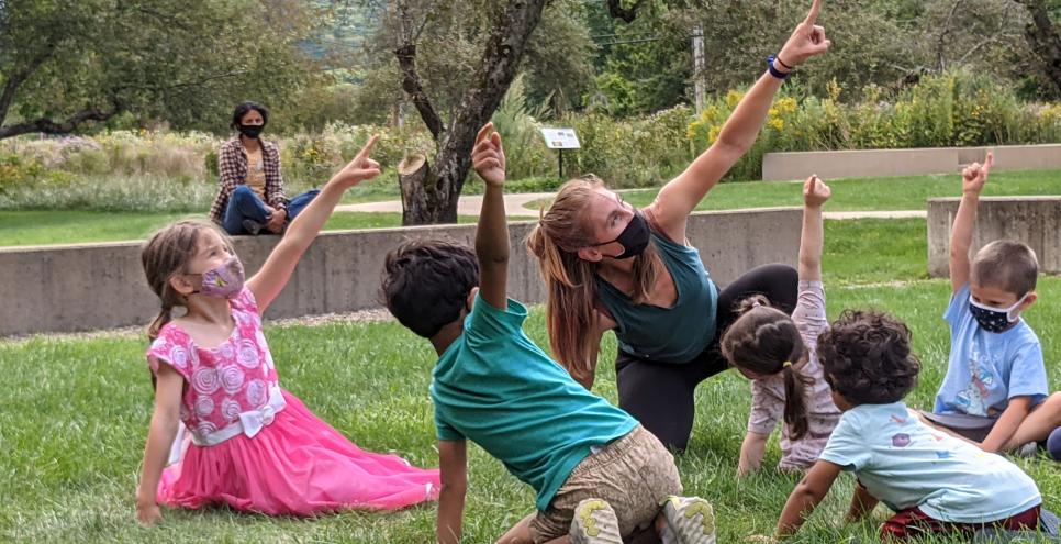 Children and instructor point up at the sky.