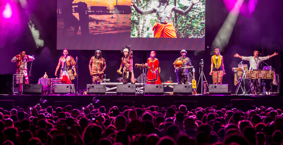 Performance with 8 people standing on a stage in front of a screen