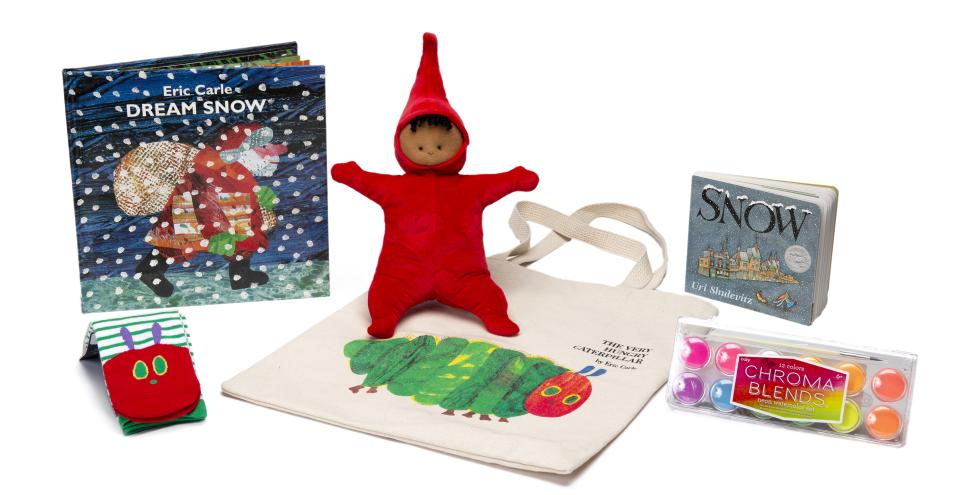 A variety of children's books, art supplies, tote bag and socks arranged on a table.