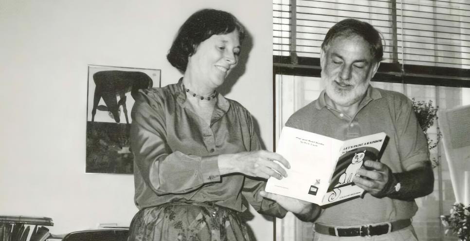 Photograph of two people reading a book together. 