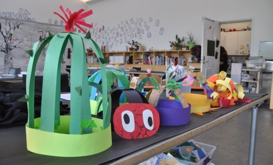 A line-up of paper hats, including a cactus hat, a caterpillar hat, and a space themed hat.